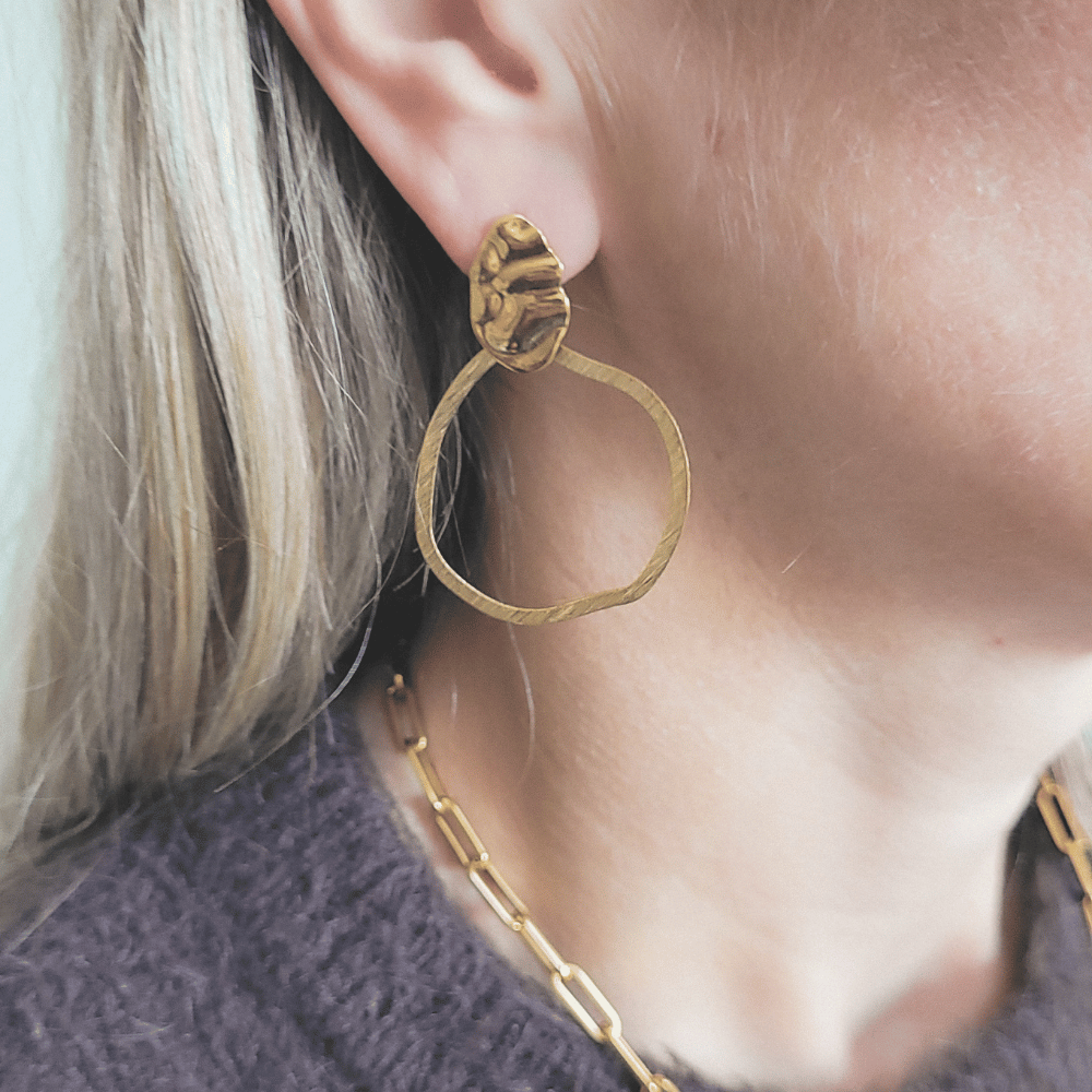 Grote gouden statement oorbel Elodie met organische open hanger, gedragen aan het oor